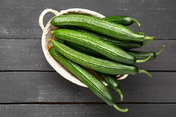 Basket with fresh cucumbers on dark wooden background