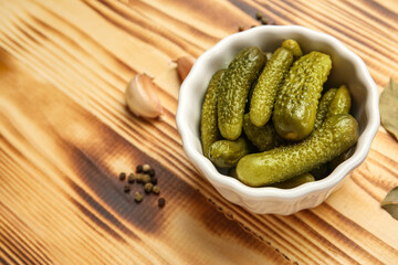 Bowl with tasty fermented cucumbers and ingredients on wooden background