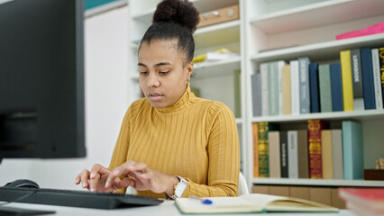 Young african american woman student using computer studying at the library