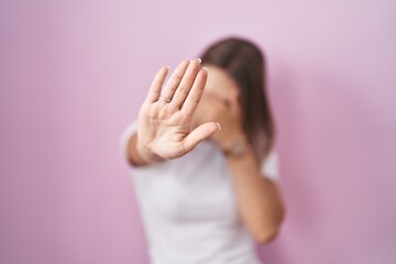 Blonde caucasian woman standing over pink background covering eyes with hands and doing stop gesture with sad and fear expression. embarrassed and negative concept.