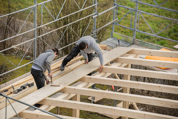 Two young carpenters building a carport. - obrazy, fototapety, plakaty