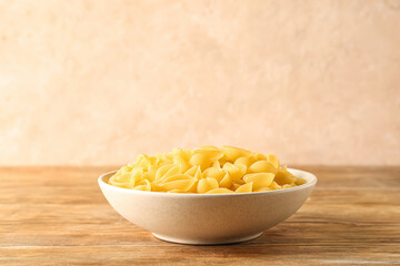 Bowl with raw conchiglie pasta on table
