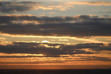 Sunset sky with red light of the setting sun. Evening clouds in the orange light of sunset rays