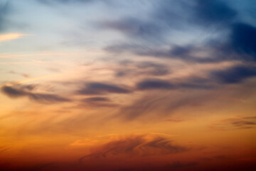 Sunset sky with red light of the setting sun. Evening clouds in the orange light of sunset rays