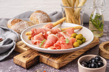 Plate with slices of tasty jamon on table