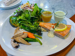 Salmon steak and salad on white dish.