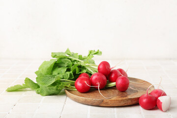 Plate of ripe radish with green leaves on table