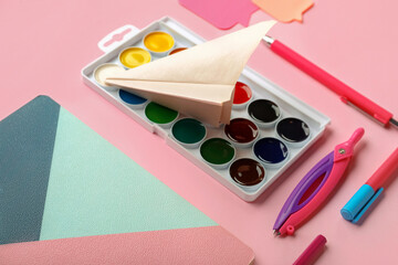 Composition with stationery supplies and paper plane on pink background