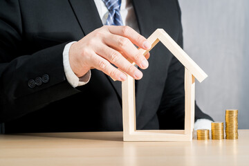 Businessman saving gold coins with invest and hand hold the home model is destination for the...