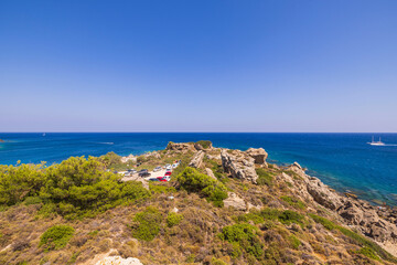 Beautiful view of mountainous Mediterranean coast with car parking in distance. Greece.