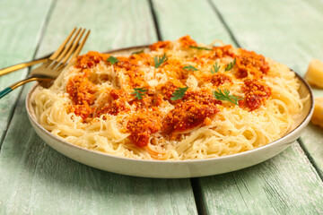 Plate of tasty Italian pasta with Parmesan cheese on light wooden background