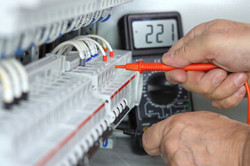 Measurement of electrical circuit parameters using a multimeter in an electrical switchboard.
