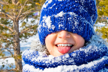 a perky boy shows his tongue in a blue hat