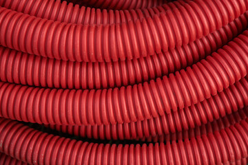 Corrugated for insulation cable of wires underground, plastic tube, electricity protection pipe for construction works, red corrugation close-up with copy space. High quality photo