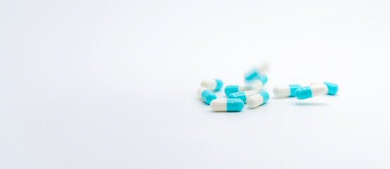 Antibiotic capsules pill falling on white background. Pharmacy banner. Antibiotic drug resistance. Prescription medicine. Medical healthcare concept. Pharmaceutical industry. Blue-white capsule pill.