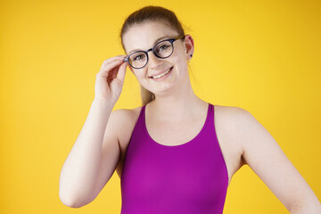Portrait of a beautiful happy smiling woman with glasses in pink one piece swimsuit in front of...