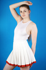Beautiful sporty woman is wearing a white tennis dress in studio