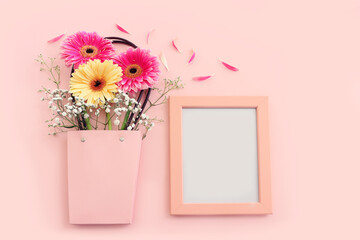 top view of flowers and elegant empty frame over pink pastel background. For mock up, copy space