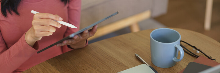 Young businesswoman reads business data on laptop and writing notes in tablet while working at home