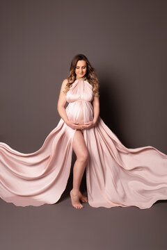 Happy pregnant girl. beautiful pregnant woman with long blond hair on a chocolate background. Pregnancy studio shooting