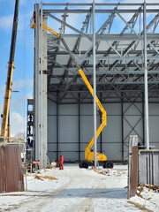Industrial site under construction in winter. Installation of the roof by mobile crane under the construction building in the factory. The process of installation of metal structures large building.