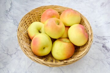 Top view of a wooden basket with apples on a marble table