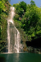 Vertical shot of a waterfall flowing into a pool on the island