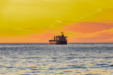 ship moving away towards the horizon during sunset