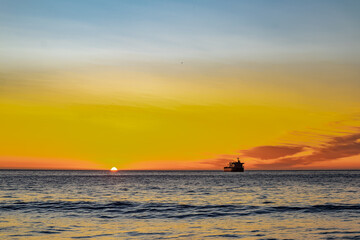 ship moving away towards the horizon during sunset