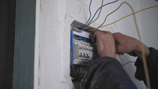 electrician installs an electrical panel in the apartment