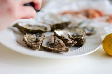 Selective focus of fresh oysters being seasoned on traditional fish market