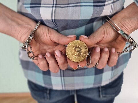 Closeup woman hands thief holding golden bitcoin in handcuffs