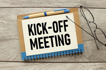 Office wooden table with paper, glasses written Kick-off meeting message. with pen, top view...