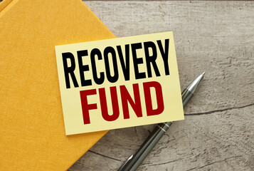 Obraz premium recovery fund yellow sticker on a yellow notebook. on a wooden table