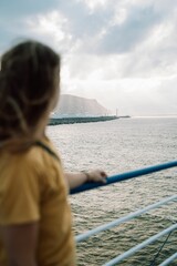Vertical shot of a girl looking at the sea from the ferry in a selective focus