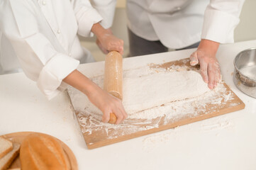 Young Asian father and his son wearing chef uniform baking together in kitchen at home