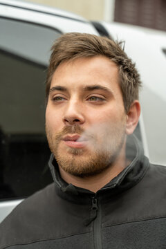 Jeune homme qui fume en ext&eacute;rieur, recrachant la fum&eacute;e de sa cigarette