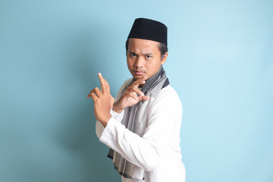 Portrait of Asian muslim man in white koko shirt doing martial arts gesture or pencak silat. Isolated image on blue background