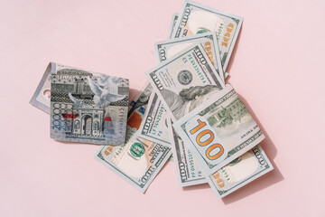 One hundred dollar bills and tenge on a pink background.