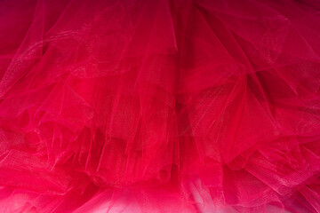 Red background of tulle fabric close-up.