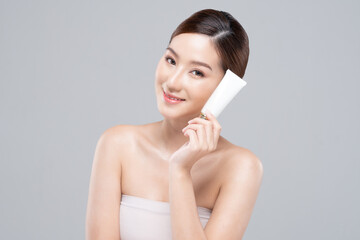Beautiful Young Asian Woman Holding luxury white clean tube smile feeling so happy and cheerful with healthy Clean and Fresh skin,isolated on gray background,Beauty Cosmetics spa and treatment Concept