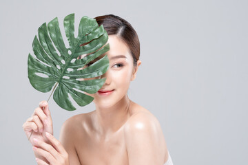 Young Beautiful Asian woman smile with clean and fresh skin with green leaf cover on face,isolated on white background,Beauty Cosmetics and spa Treatment Concept