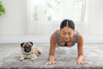 Asian woman doing yoga with her pug breed dog in a peaceful setting, cultivating a sense of harmony...