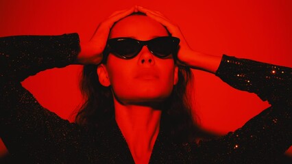 Young beautiful confident brunette female in trendy evening shiny green reflecting dress. Sexy carefree woman isolated on red neon light in studio. Fashionable model. high fashion - Powered by Adobe