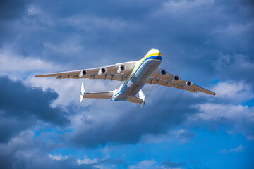 A large cargo plane flies in the blue sky. Aviation air transport. Airplane symbol. Travel background.