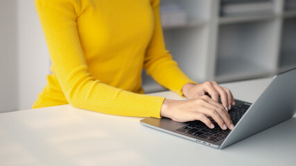 Person typing on laptop keyboard, businessman working on laptop, he is typing messages to colleagues and making financial information sheet to sum up the meeting.