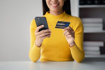Beautiful woman holding a credit card, she uses a credit card to pay for goods and services online, the concept of using a credit card for online shopping, ordering goods and services on the website.
