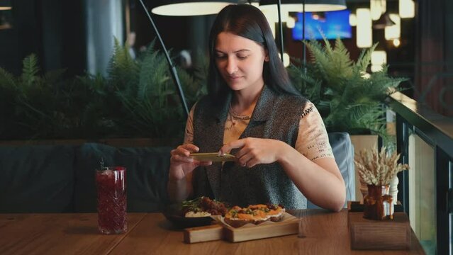 Woman blogger taking pictures of food in a restaurant