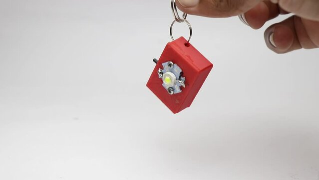 Flashlight or small torchlight made from 3d printing technology held in hand hanging as a key chain. Survival small flash lamp