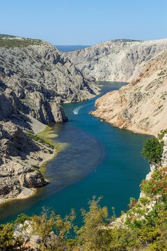 Scenic vertical drone shot of a river surrounded by rocky hills in Croatia © Llcinema/Wirestock Creators